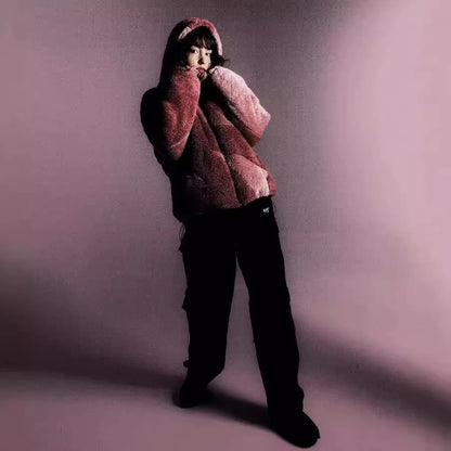 Person wearing a pink fuzzy hoodie and black pants against a purple background